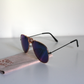 Sunglasses with blue-green lenses and matte-black arms. Beer Eyed sunglasses cloth under sunglasses. Right-view