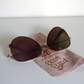 Sunglasses with rose-gold lenses and matte-rose arms.  Beer Eyed sunglasses cloth under sunglasses. 